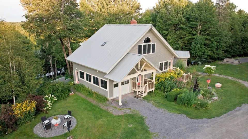 Aerial view of the Dragonwood main house, gardens, and pond beyond the trees