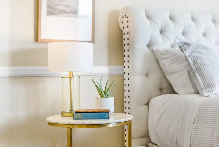 Furnished bedroom detail with neutral linens and bedside lighting